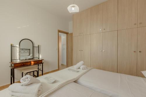 een witte slaapkamer met een bed en een spiegel bij House on the black beach with sea view and parking in Agios Georgios Thalassiti