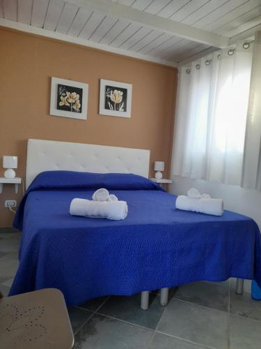 1 dormitorio con 1 cama azul y 2 toallas en CasaMya, en SantʼAntìoco