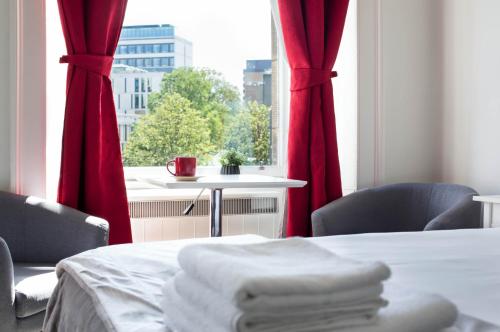 a room with two beds and a window with red curtains at Modern Studio Apartment in prime central location in Edinburgh