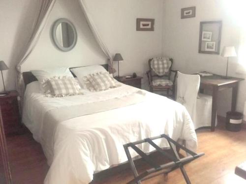 a bedroom with a white bed with a desk and a chair at Logis Hôtel Le Clos Pité in Préchacq