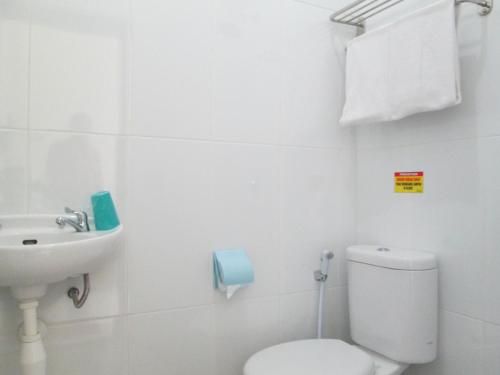 a white bathroom with a toilet and a sink at Mahkota Hotel in Genteng-kulon