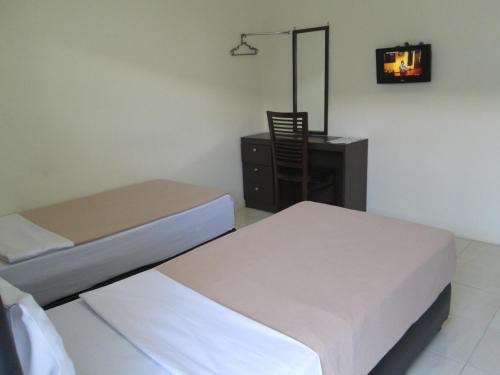 a bedroom with two beds and a dresser with a mirror at Mahkota Hotel in Genteng-kulon