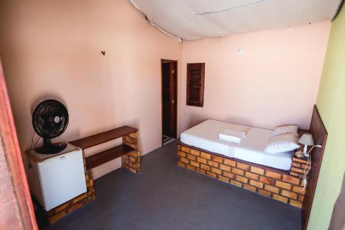 a small room with a bed and a brick wall at Pousada Recanto Verde in Parajuru