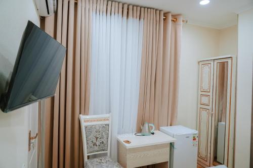 um quarto com uma televisão e uma secretária com uma cadeira em Oasis Boutique em Bukhara