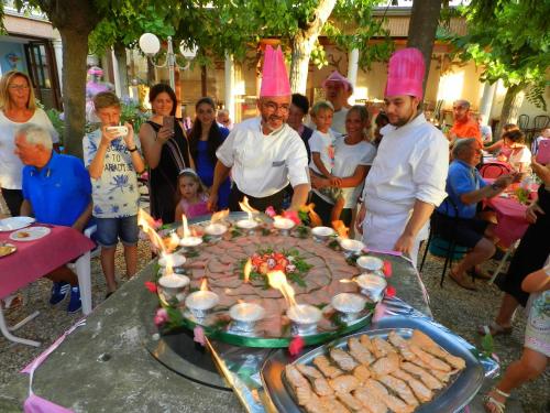 a group of people standing around a table with a large cake at Hotel Villa Fulgida in Cattolica