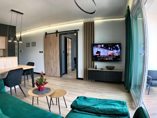 Una sala de estar con un sofá, una mesa y un televisor. en Loftowe UkieLove, en Olsztyn