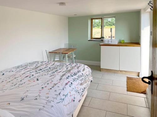 a bedroom with a bed and a table and a kitchen at The Hut in Ross on Wye