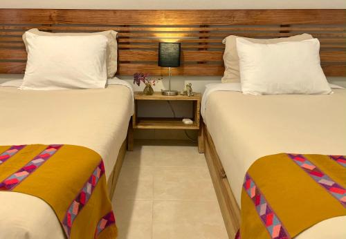 two twin beds in a room with a night stand at Hotel Casa Azabache in San Cristóbal de Las Casas