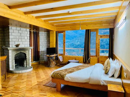 a bedroom with a large bed and a fireplace at Vashisht valley hotel in Manāli