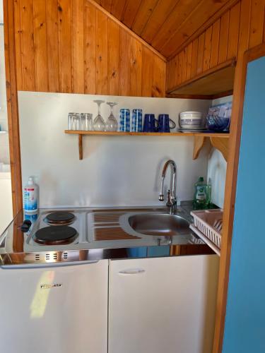 a kitchen with a stove and a sink and wooden cabinets at Perun Guest House in Mlini