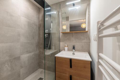 La salle de bains est pourvue d'un lavabo et d'une douche. dans l'établissement AMJA Proche clinique Saint-Roch apt 3 chambres 3 salles de bain parking gratuit idéal famille groupe coworking 10 min centre ville 10 min plage 5 min sortie autoroute, à Montpellier