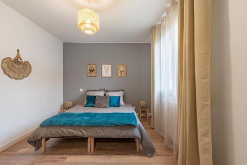 une chambre avec un lit avec des draps bleus et une fenêtre dans l'établissement AMJA Proche clinique Saint-Roch apt 3 chambres 3 salles de bain parking gratuit idéal famille groupe coworking 10 min centre ville 10 min plage 5 min sortie autoroute, à Montpellier