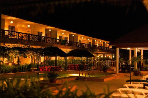 a hotel at night with a pool and tables and chairs at Bamboo Garden Hotel in Serekunda