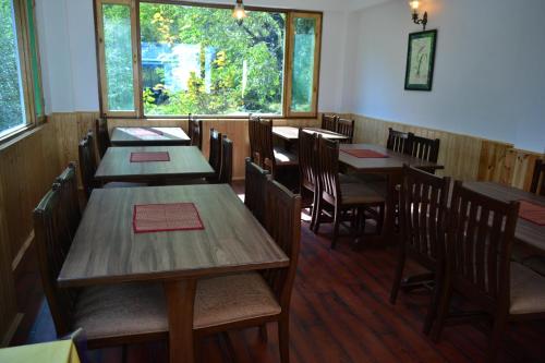 a dining room with wooden tables and chairs at Hotel Delfryn in Manāli