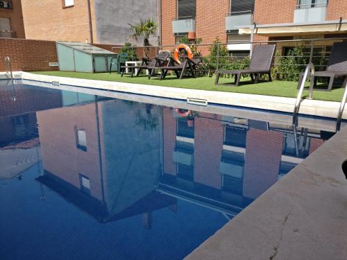 a person sitting on a bench in a swimming pool at Hotel Apartamentos Don Juan I in Alcalá de Henares