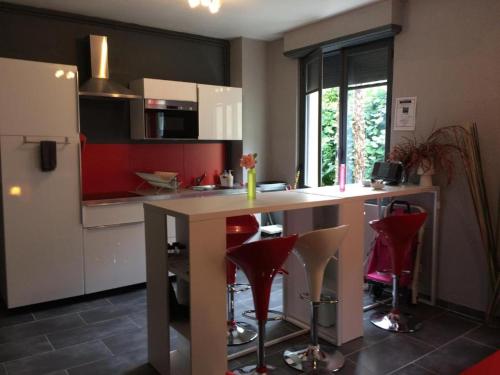 une cuisine avec un comptoir et quelques chaises rouges dans l'établissement LE LOGIS LE PIC DU MIDI et LE LOGIS LE COL D'ASPIN, à Lourdes