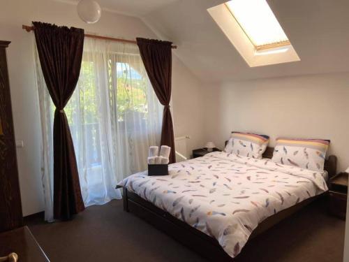 - une chambre avec un grand lit et une fenêtre dans l'établissement Pensiunea Rares, à Bistriţa Bîrgăului