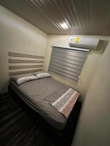 ein kleines Bett in einem kleinen Zimmer mit Fenster in der Unterkunft Sol y Luna Pedasí in Pedasí Town