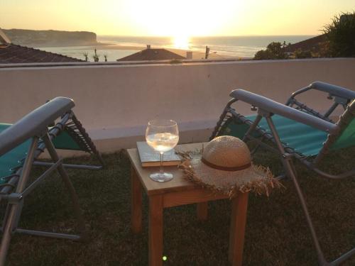 a hat and a glass of wine sitting on a table at Foz - Sea View Cottage in Foz do Arelho