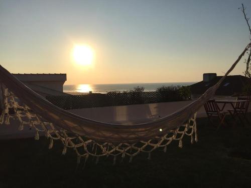 a hammock with the sunset in the background at Foz - Sea View Cottage in Foz do Arelho
