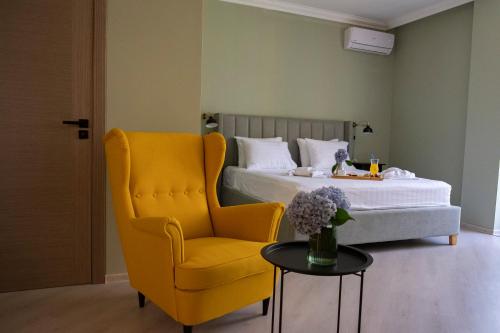 a bedroom with a bed and a yellow chair and a table at Buxus Hotel Shekvetili in Shekvetili