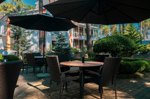 a table and chairs with umbrellas on a patio at Buxus Hotel Shekvetili in Shekvetili