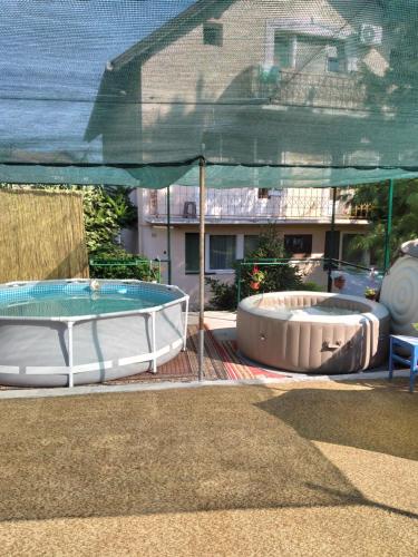 2 bañeras de hidromasaje grandes en un patio con sombrilla en HOSTEL BATA APARTMANI, en Kanjiža