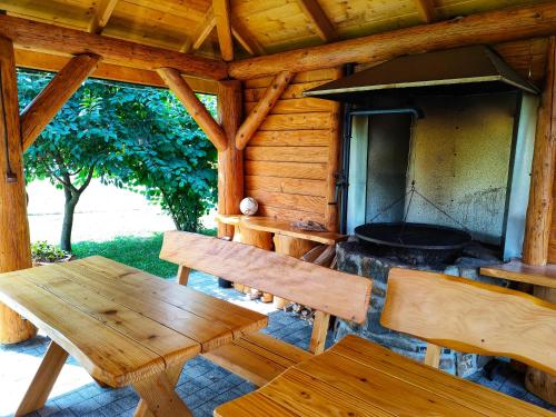 a wooden cabin with a table and benches and a grill at Chatki U Hanusi in Czchów