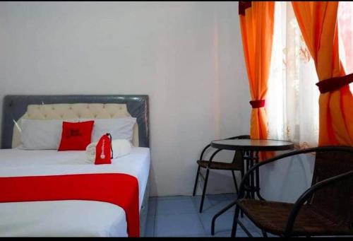 Schlafzimmer mit einem Bett mit einem roten Kissen und einem Tisch in der Unterkunft Hotel Near Ramayana 3 in Pekalongan