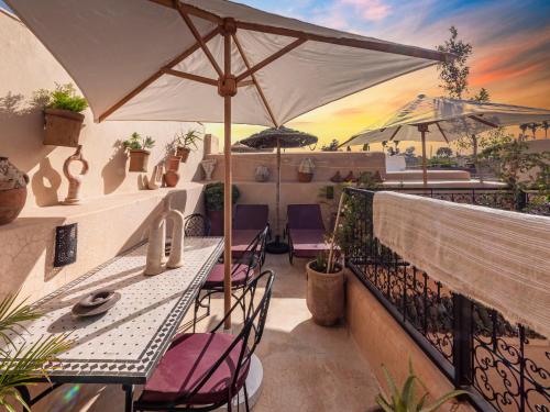 a balcony with tables and chairs and an umbrella at Riad Oumnia - Top emplacement - Riad en entier pour vous in Marrakesh