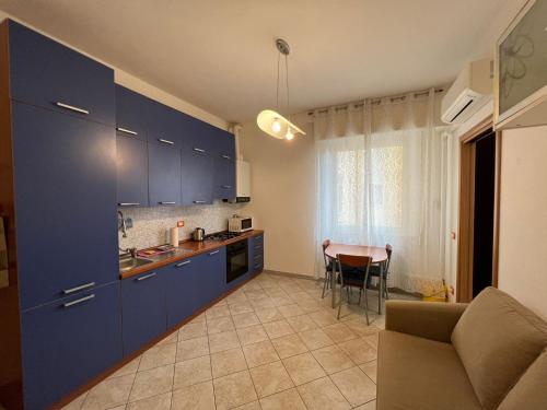 une cuisine avec des placards bleus et une table avec un canapé dans l'établissement Savona Sant'antonio Mare Clima WiFi, à Savone