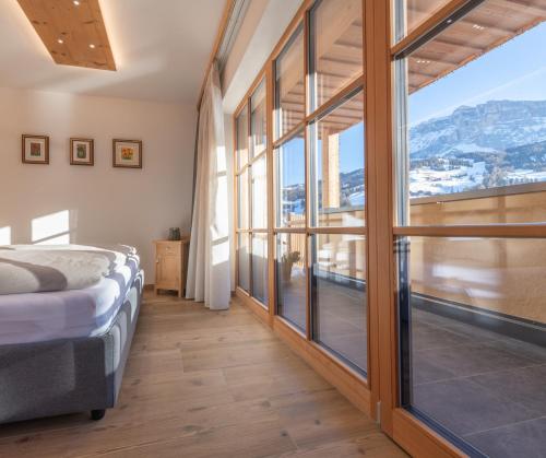 a bedroom with a bed and a large window at Ciasa Nene Franzl in Badia