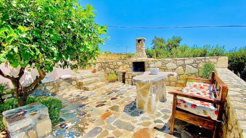 a stone patio with a stone fireplace and a tree at Orionas in Tsoútsouros