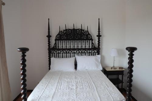 1 cama con cabecero de madera y sábanas y almohadas blancas en Casa do Cipreste, en Viana do Castelo