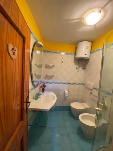 uma casa de banho com 2 WC, um lavatório e um espelho. em Casa di famiglia em Casaletto Spartano