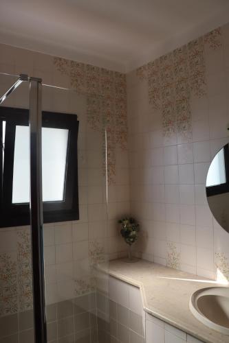 ein Bad mit einer Dusche, einem Waschbecken und einem Fenster in der Unterkunft Casa do Cipreste in Viana do Castelo