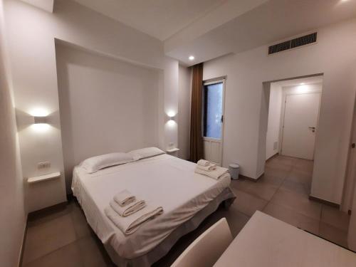 a bedroom with a bed with white sheets and a window at Antares Rooms and Suites in Olbia