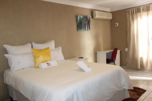 a bedroom with a large white bed with yellow pillows at Unit G Guest House in Ga-Mothiba
