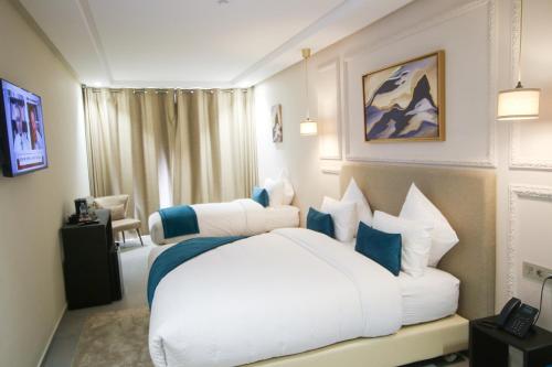 a bedroom with a large white bed with blue pillows at Dakhla Boarding Hotel & Restaurant in Dakhla