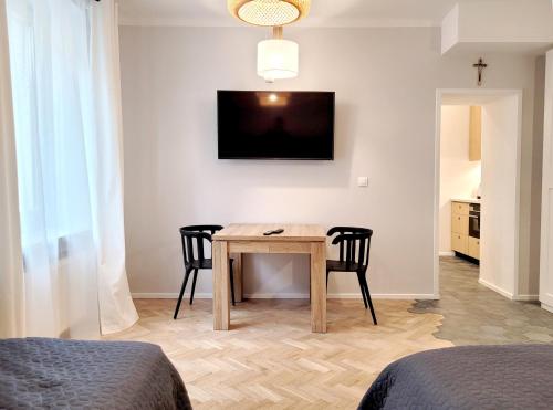 een kamer met een tafel en twee stoelen en een televisie bij Kana Apartment Kraków Pomorska - close, fast WiFi, Smart TV in Krakau