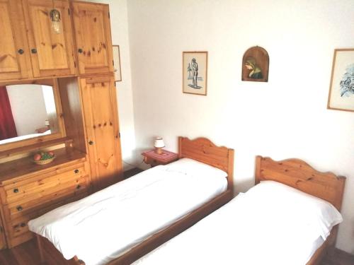 1 dormitorio con 2 camas y armario de madera en La taverna di Susanne, en Valle di Cadore