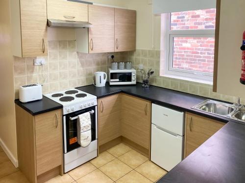 a small kitchen with a stove and a microwave at Headrose House in West Bromwich