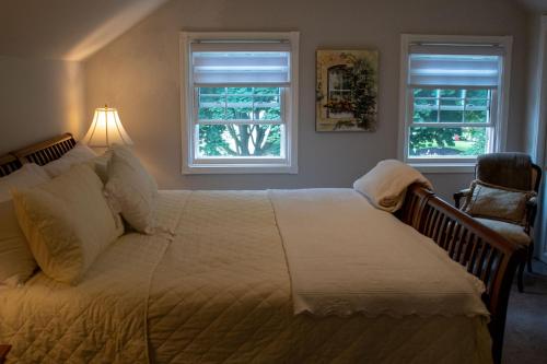 ein Schlafzimmer mit einem großen Bett und zwei Fenstern in der Unterkunft Upper Canada Coach House in Niagara on the Lake