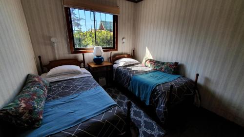 two beds sitting in a room with a window at La Casa del Tata, El Quisco in El Quisco