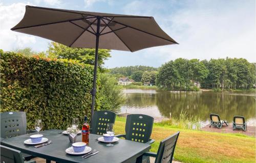 a table with an umbrella in front of a lake at 3 Bedroom Cozy Home In Vlagtwedde in Vlagtwedde