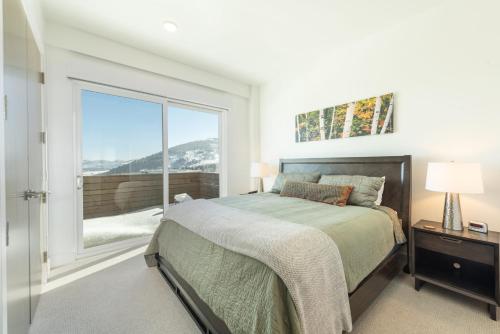 um quarto com uma cama e uma grande janela em Elevated Living Slopeside Mountain Luxury 5 Bedroom Private Hot Tub Ski In Ski Out End Unit Townhome em Park City