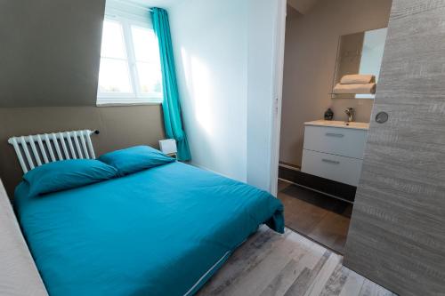 a bedroom with a blue bed and a window at Au coucher de soleil - Dormir comme à la maison - in Châteaubriant