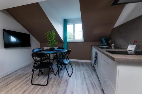 une cuisine avec une table, des chaises et un évier dans l'établissement Au coucher de soleil - Dormir comme à la maison -, à Châteaubriant