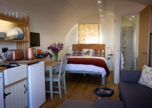 ein Schlafzimmer mit einem Bett und eine Küche mit einem Tisch in der Unterkunft Culkein Pods in Lochinver
