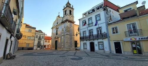 an old building with a clock tower in a street at Seixal Bay House!! in Seixal
